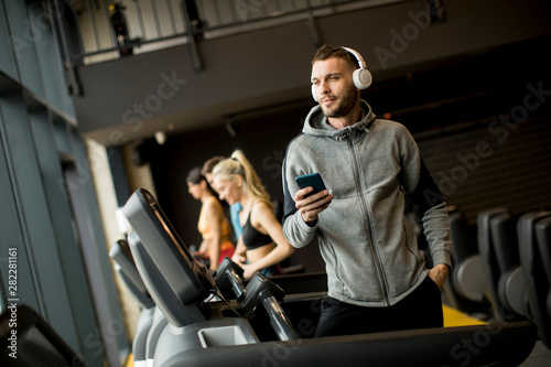 Smiling sporty man listening to music in gym