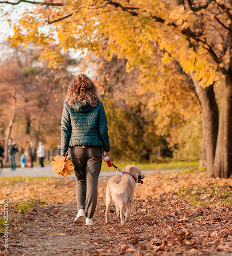 Portrait of a young woman with dog on golden autumn walk.