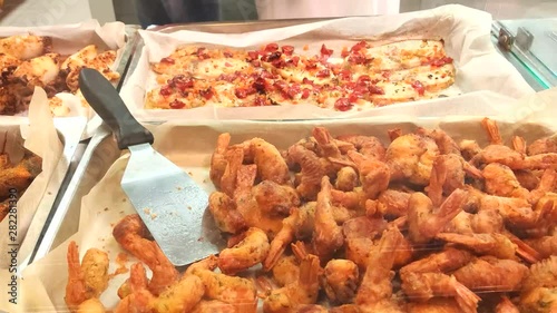 ready-made fish and grilled shrimps made fish and grilled shrimps street foods, fast food. In the supermarket, the seller lays the finished fish and fried shrimp in the container to the buyer