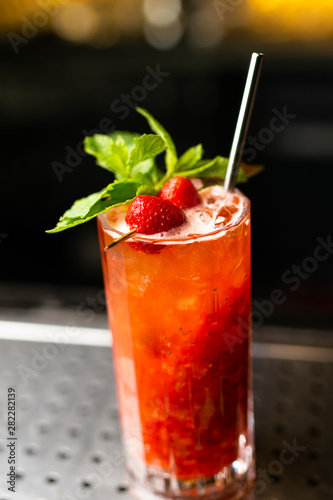 Lemonade cocktail with strawberry and mint on the bar, blurred background.