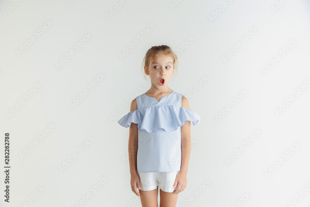 Stylish little smiling girl posing in casual clothes isolated on white background. Caucasian blonde female model. Human emotions, facial expression, childhood. Shocked, thoughtful, looking at side. Stylish little smiling girl posing in casual clothes isolated on white background. Caucasian blonde female model. Human emotions, facial expression, childhood. Shocked, thoughtful, looking at side.