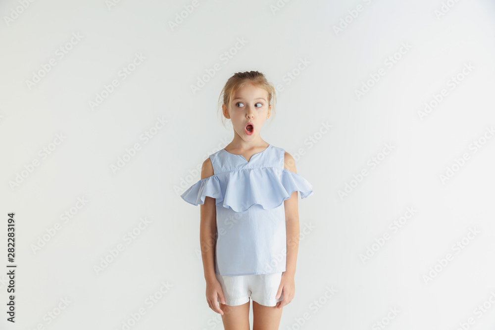 Stylish little smiling girl posing in casual clothes isolated on white background. Caucasian blonde female model. Human emotions, facial expression, childhood. Shocked, thoughtful, looking at side. Stylish little smiling girl posing in casual clothes isolated on white background. Caucasian blonde female model. Human emotions, facial expression, childhood. Shocked, thoughtful, looking at side.