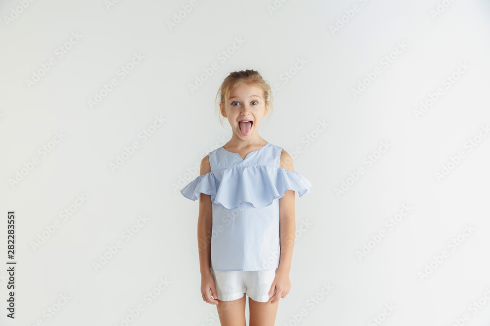Stylish little smiling girl posing in casual clothes isolated on white studio background. Caucasian blonde female model. Human emotions, facial expression, childhood. Smiling, grimaces. Stylish little smiling girl posing in casual clothes isolated on white studio background. Caucasian blonde female model. Human emotions, facial expression, childhood. Smiling, grimaces.
