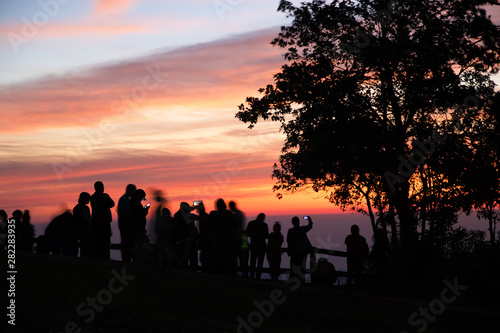 Dramatic landscape of silhouette people taking photo with beautiful sunrise at the peak of Phu Ruea National Park in Loei Province, Thailand.
