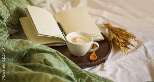 Cozy coffee cup cappuccino with notebook and pen in wooden board , morning bed coffee, vintage coffee cuo, morning coffee still life