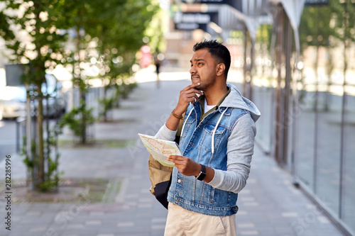 travel, tourism and backpacking concept - indian man traveling with backpack and map in city searching location photo