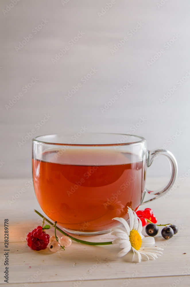 tea in a mug with berries and chamomile on a white background tea in a mug with berries and chamomile on a white background