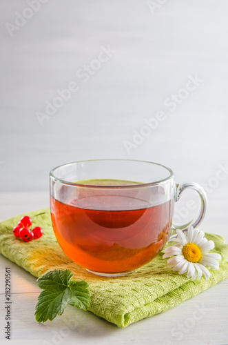 tea in a mug with berries and chamomile on a white background
