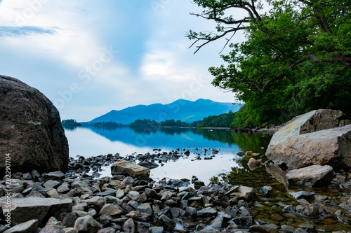 Stones in the lake with a fragment of a pebble beach with mountains nicely reflected in the water - Keswick, Lake District, United Kingdom