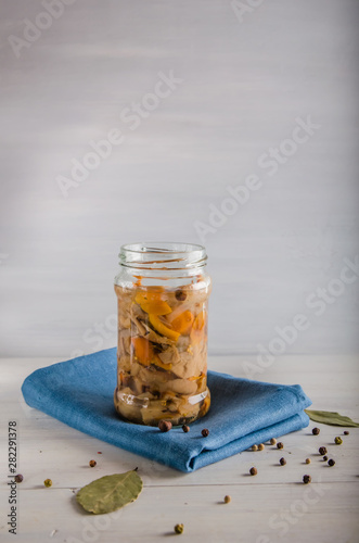 pickled mushrooms in a glass jar on a white background