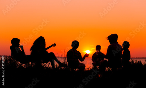 Silhouette of people sitting on the beach with campfire at sunse