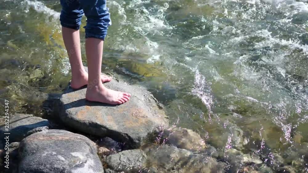 Mountain river. The guy is standing on a rock, the water flows around his feet and stone .Early morning traveler.