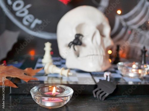 Decorative composition for interior decoration for Halloween, skull, burning candles, decor, autumn leaves, illumination on a black background with the inscription October 31