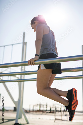 Beautiful woman doing dips on bar at outdoor training spot or street workout in Barcelona beach (SPAIN)