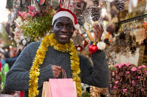 Guy in Santa hat choosing Christmas decorations