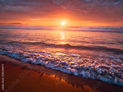 beautiful red sunset on beach with a wave on the shore