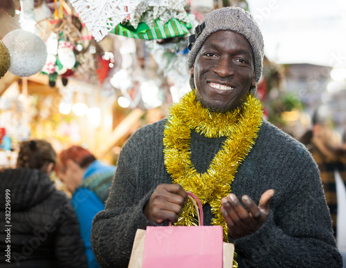 Smiling man with shopping bags on Christmas fair