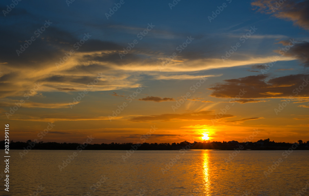 Beautiful Sunset in the sky with sky blue and orange light of the sun through the clouds in the sky, Orange and red dramatic colors over the sea. - Image