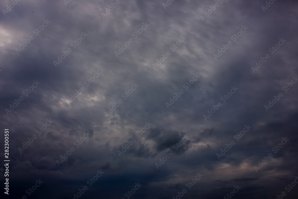 Dark rain clouds during sunset. Dramatic sky during sunset. Dark storm clouds with black and white highlights.