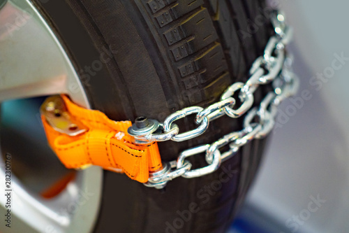 Chains for riding in the snow. Anti-slip agent. Chain on wheels against slipping. Driving safety in winter. Chains are mounted on the wheel of a car. Ensuring safe driving in the snow. Anti-slip agent