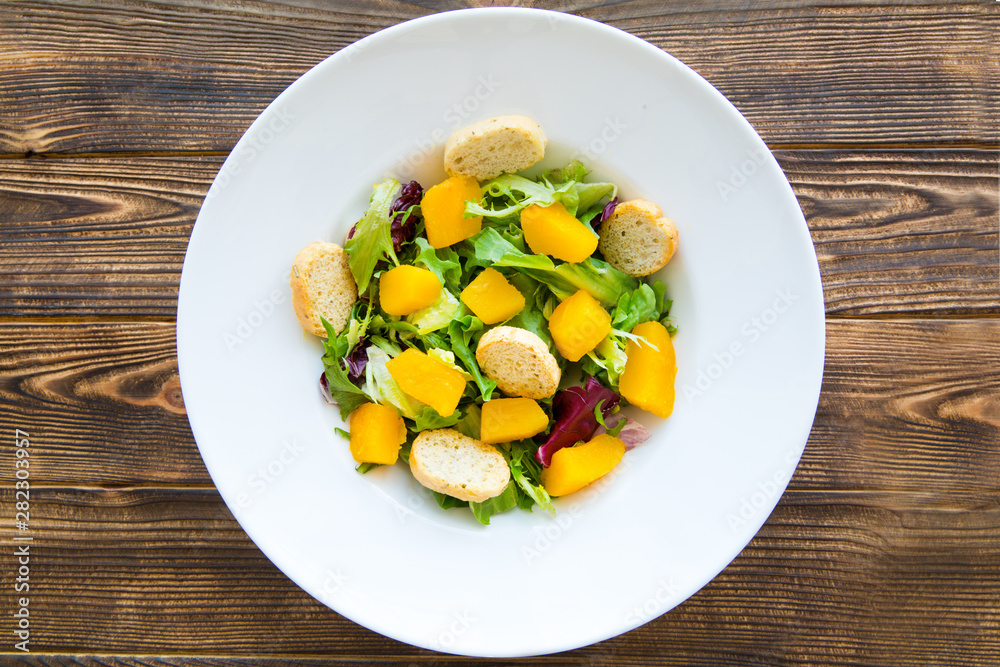 Tasty pumpkin salad with croutons and greens on brown wooden rustic table. Top view. Autumn (fall) food. Tasty pumpkin salad with croutons and greens on brown wooden rustic table. Top view. Autumn (fall) food.