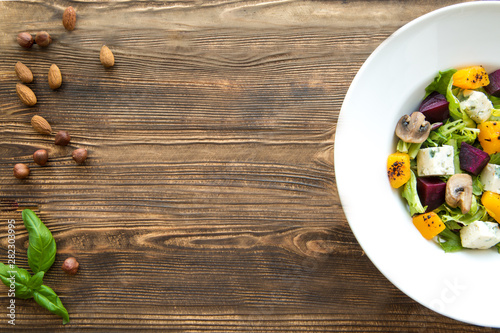 Pumpkin salad with beetroot, grilled mushrooms and cheese on brown rustic table. Space for text, copy space. 