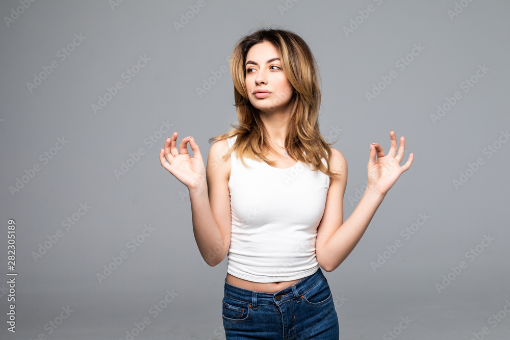 Happy young woman gesturing ok smiling isolated on gray background Happy young woman gesturing ok smiling isolated on gray background