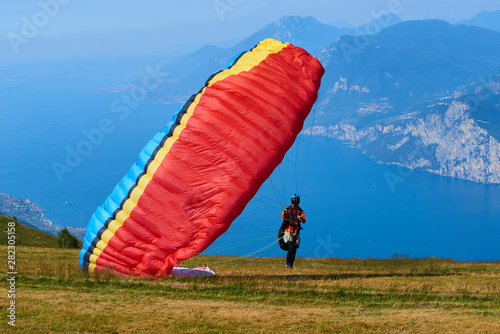 Paraglider flying over the Garda Lake (Lago di Garda or Lago Benaco). Paragliding on Monte Baldo. Panorama of the gorgeous Garda lake surrounded by mountains, Malcesine, Italy