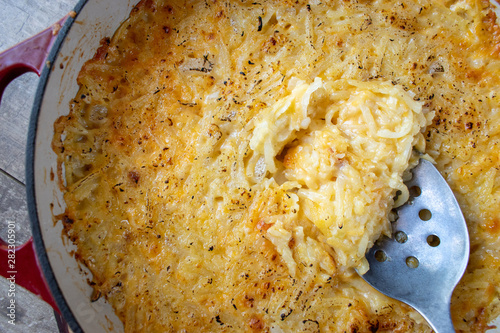 Obraz na plátně Cheesy potato hash browns in cast iron dish flat lay