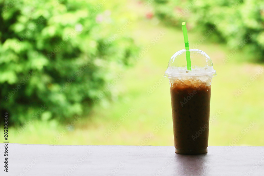 Cold coffee is placed on a wooden table in the midst of nature. Cold coffee is placed on a wooden table in the midst of nature.
