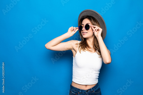 Portrait of pretty woman in sunglasses and hat over blue colorful background © dianagrytsku