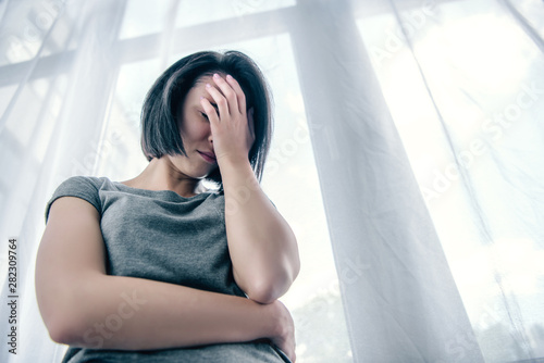 low angle view of depressed woman covering face at home