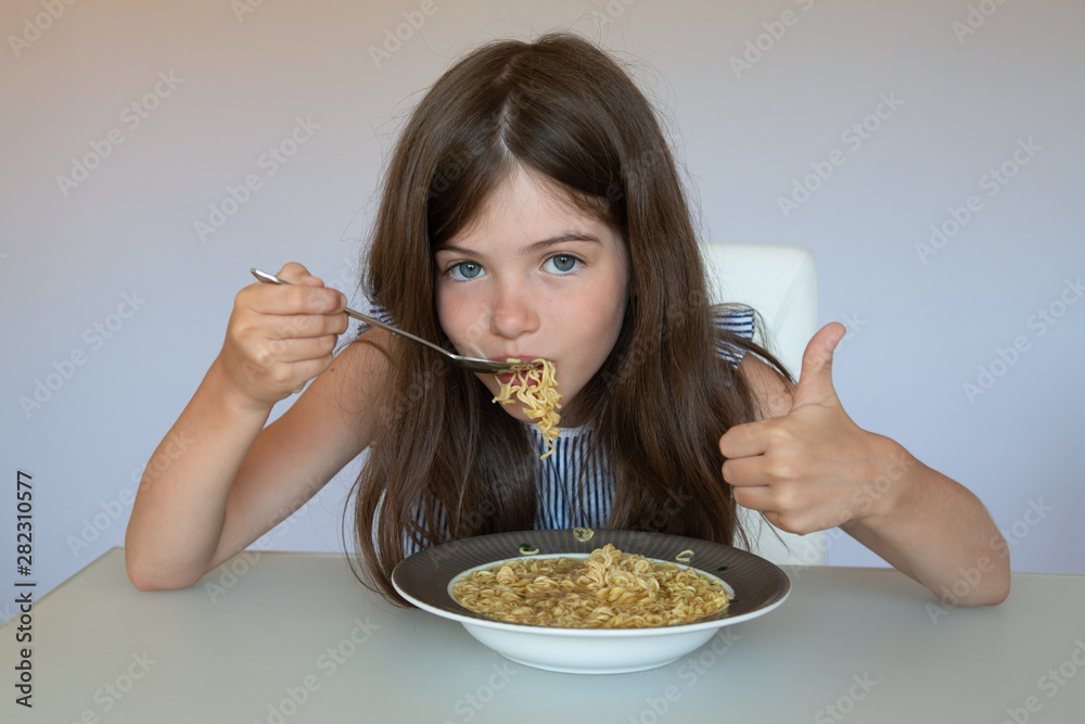 little girl eating chinese instant noodles, unhealthy eating concept, food addiction little girl eating chinese instant noodles, unhealthy eating concept, food addiction