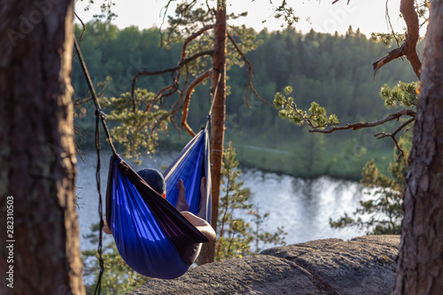 Moody sunset photo of a man in a hammock. Shallow depth of field and a low angle.