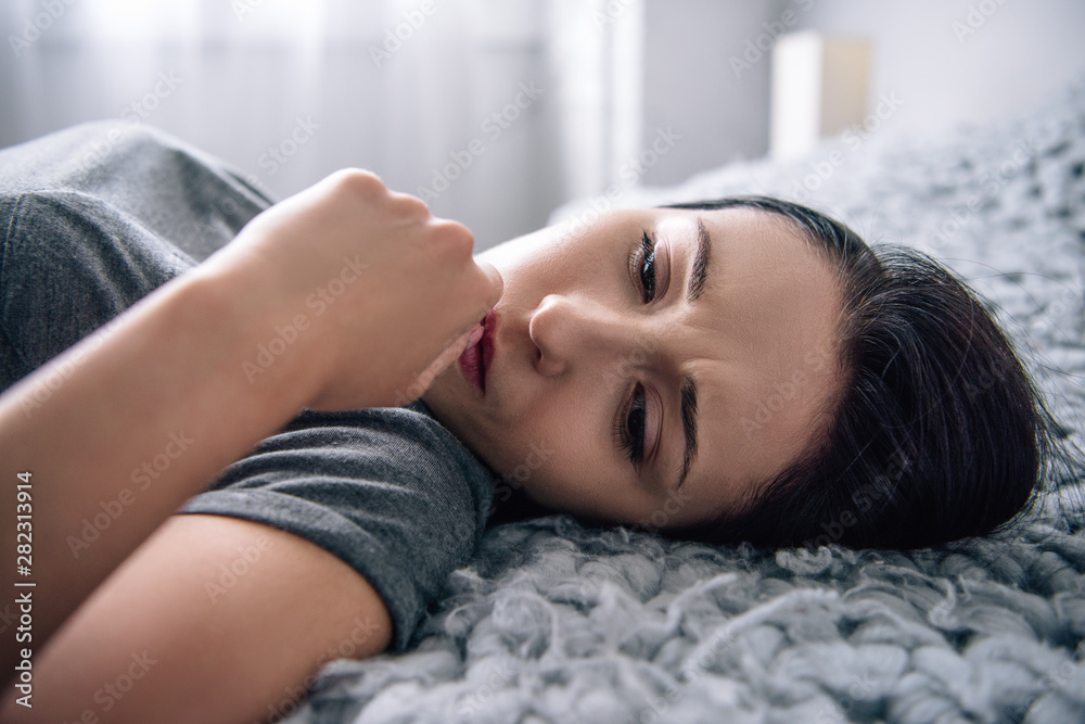 Fototapeta premium selective focus of beautiful depressed woman lying on bed at home