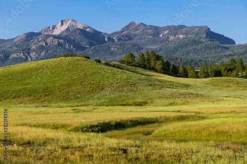 Mountain peaks above a beautiful grassy meadow and hills - the Rocky Mountains near Pagosa Springs, Colorado