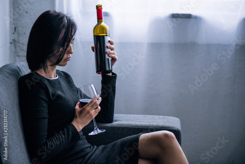 Canvas Print depressed lonely woman with wine bottle and glass at home