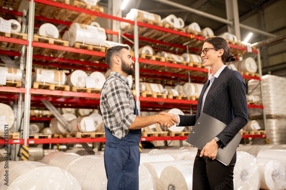 Successful partners handshaking in warehouse of large factory after negotiation