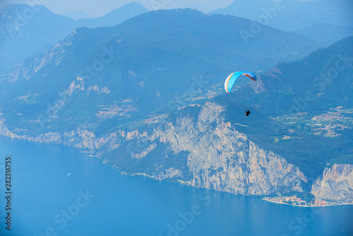 Paraglider flying over the Garda Lake (Lago di Garda or Lago Benaco), Panorama of the gorgeous Garda lake surrounded by mountains. Paragliding is very popular sport in Monte Baldo. Malcesine, Italy