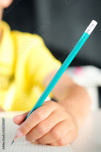 Pencil in a child's hand on a blank sheet of paper