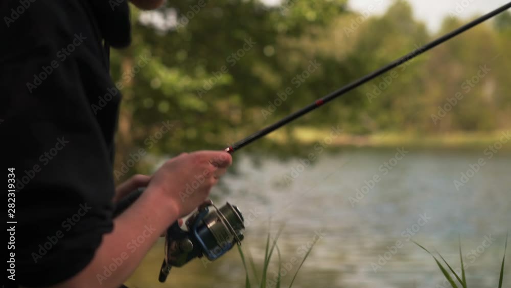 Fisherman at lake reeling in fishing line slack, closeup