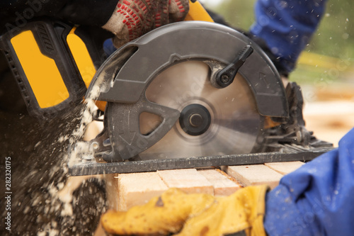 Builder uses portable circular saw tool to cut wood
