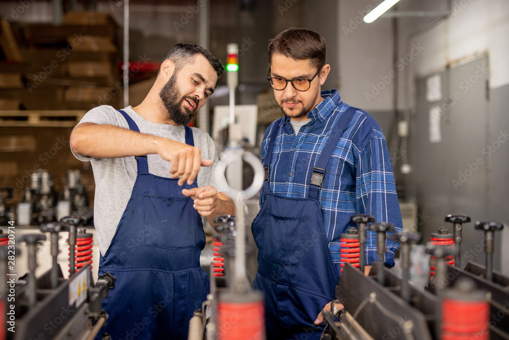Young engineer explaining his trainee how to serve and use technical equipment Young engineer explaining his trainee how to serve and use technical equipment