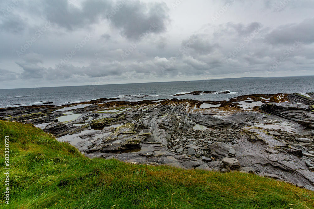 Beautiful Irish limestone landscape on the coast in the coastal walk route from Doolin to the Cliffs of Moher, geosites and geopark, Wild Atlantic Way, rainy day in county Clare in Ireland