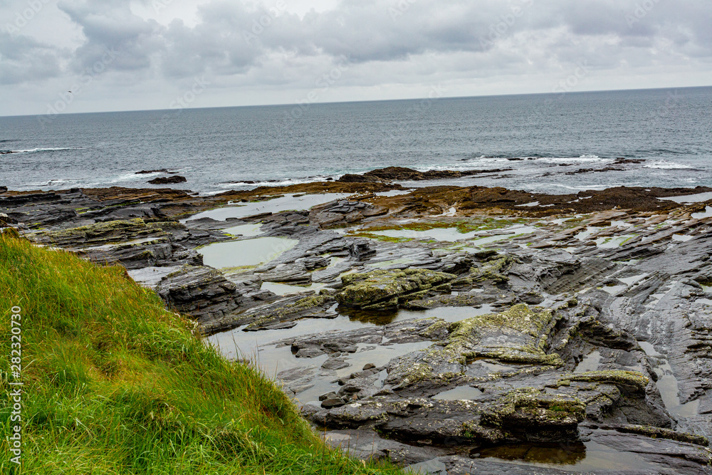 Irish limestone landscape on the coast in the coastal walk route from Doolin to the Cliffs of Moher, geosites and geopark, Wild Atlantic Way, rainy day in county Clare in Ireland