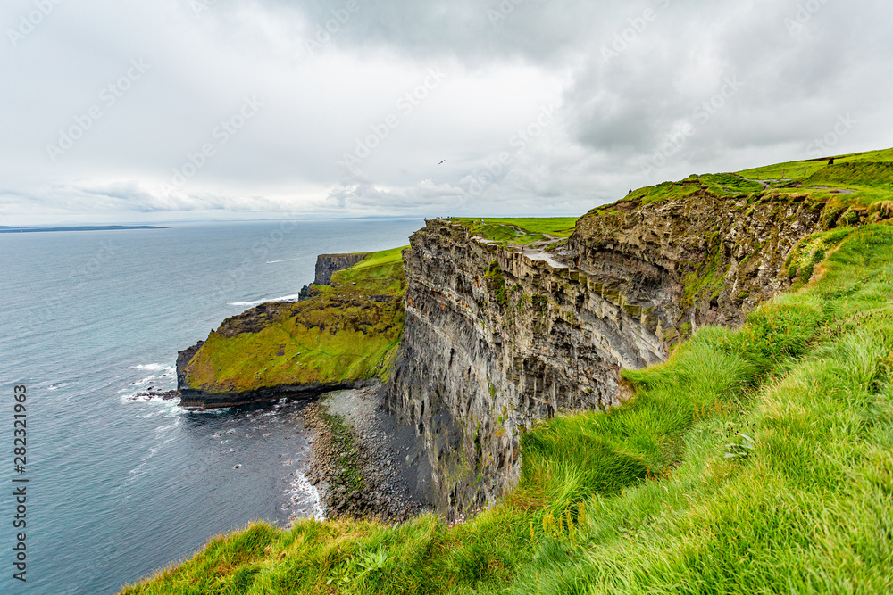 Beautiful view of the sea and the limestone rock cliffs along the coastal walk route from Doolin to the Cliffs of Moher, geosites and geopark, Wild Atlantic Way, spring day in county Clare in Ireland