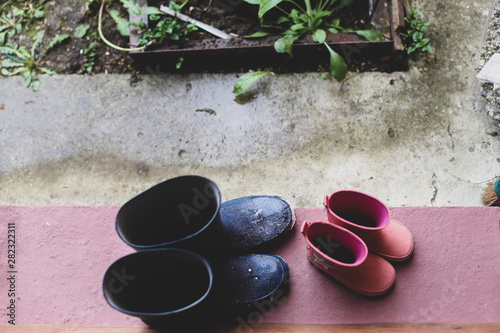 Two rubber boots pairs (father and daughter) on the porch at the entrance of the house during a rainy day4 photo