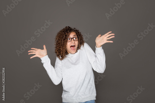Shocked young Indian woman reacts emotionally. African American girl in the studio on a black isolated background shows surprise with hands.  © Oleksandr