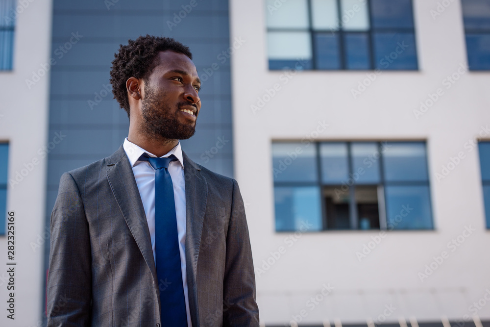positive african american businessman smiling while looking away on street positive african american businessman smiling while looking away on street