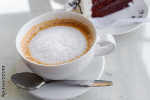 Latte coffee in a white cup on white table